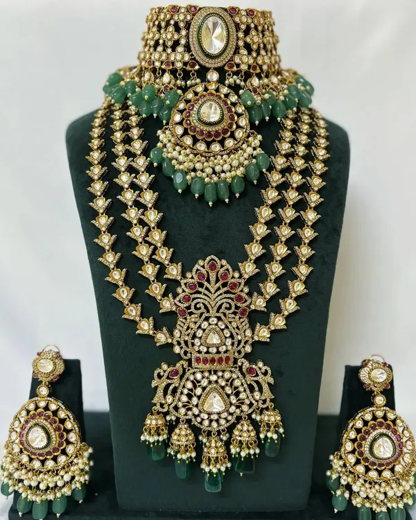 This is a complete bridal jewellery set for rent, featuring a heavy Kundan choker, a matching layered Rani Haar, and oversized earrings. The intricate design with green beads makes it a perfect choice for a traditional wedding look.