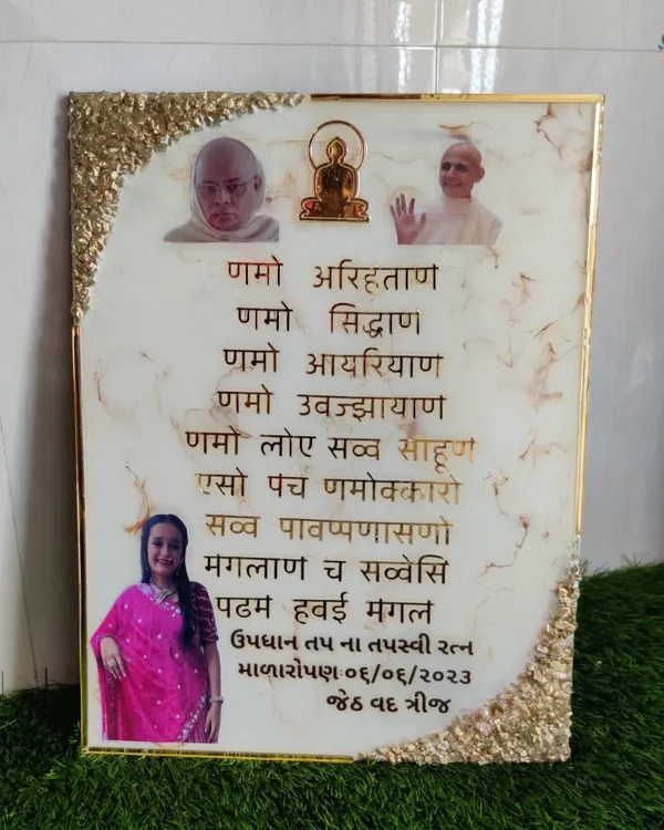 A custom Navkar Mantra frame featuring photos of revered figures and a loved one. The white marble resin is accented with a gold geode border.
