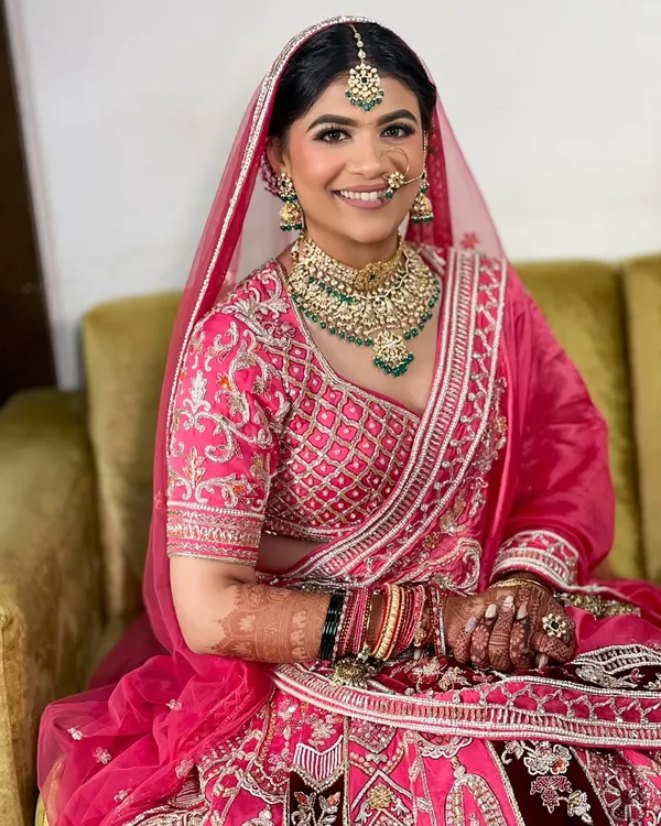 The pure joy on a bride's face is everything. For this look, I created a classic bridal updo to sit neatly under her dupatta, complementing her stunning pink lehenga.