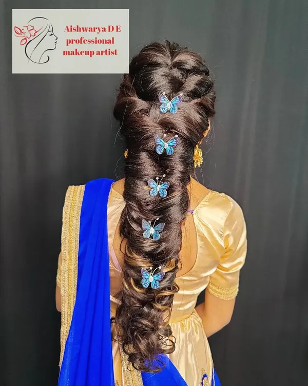 I love getting creative with hairstyles. This is an intricate pull-through braid, decorated with delicate butterfly clips for a touch of whimsy, ideal for a sangeet or special event.