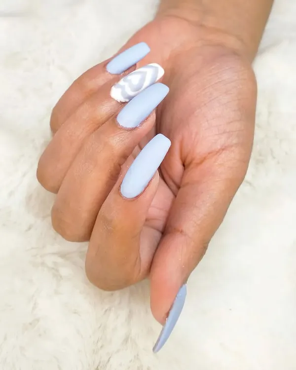 A single hand showing off the trendy sky blue manicure with a detailed, multi-layered white heart on the accent nail.
