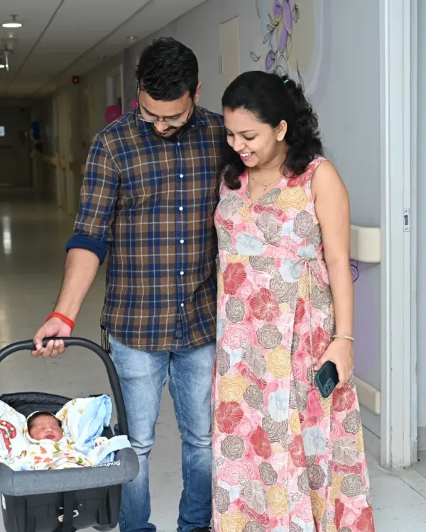 The first family photo. New parents gaze lovingly at their newborn in a car seat, just moments before taking him home from the hospital. These are the priceless memories I help capture.