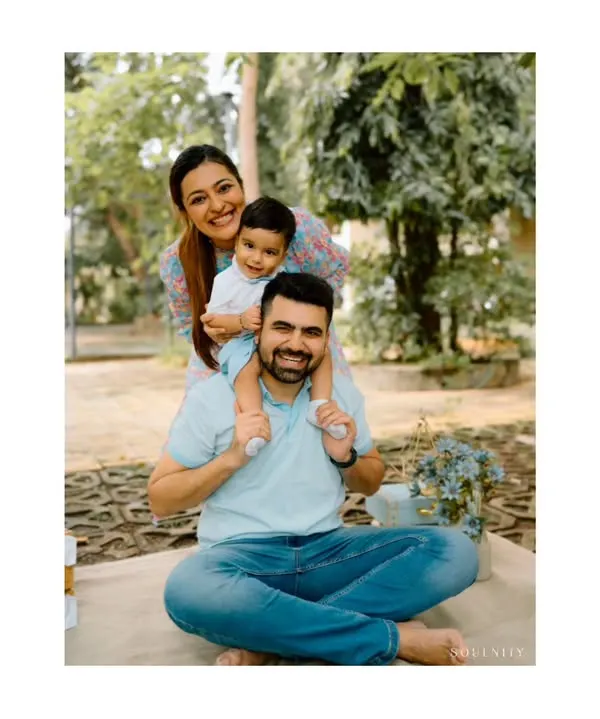 A playful "family stack" portrait during an outdoor session. The son on his dad's shoulders and the mom peeking from behind creates a fun, dynamic, and loving image.