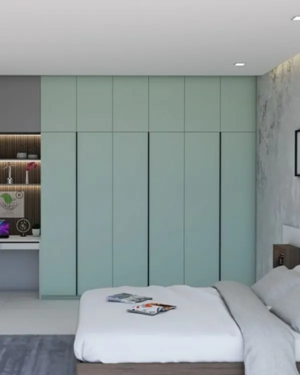 A serene master bedroom featuring a floor-to-ceiling wardrobe in a soft mint green finish. The integrated study nook with open shelving makes this a perfect multi-functional space for work and rest.