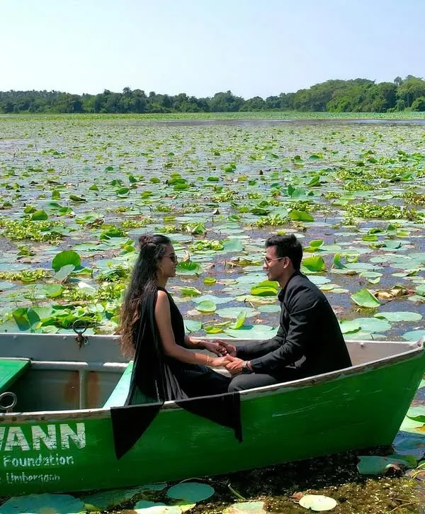 A wide shot of the couple in a boat, surrounded by a vast expanse of lily pads. This photo captures the tranquility and unique beauty of their lakeside pre-wedding shoot.