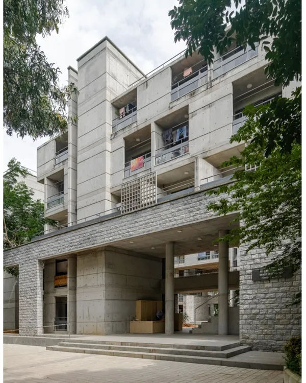 The entrance to the new hostel at IIM Bangalore, completed in 2022. The design uses a combination of exposed concrete and stone cladding to harmonize with the existing campus buildings designed by master architect B.V. Doshi.