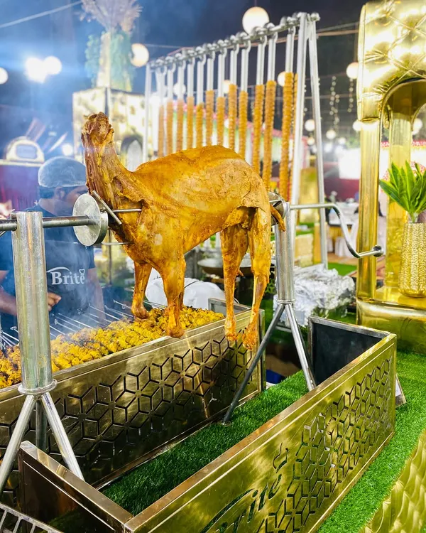 A true showstopper, this whole lamb is being roasted on a rotisserie over a live charcoal grill, creating a spectacular centerpiece for any wedding feast.