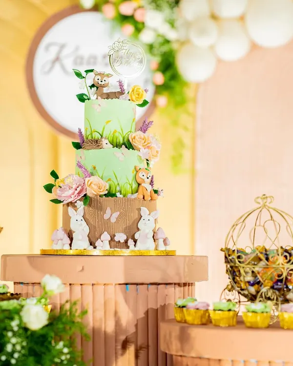 A beautiful woodland-themed cake with three tiers, decorated with adorable fondant animals like bunnies, a fox, and a deer, all nestled among flowers.