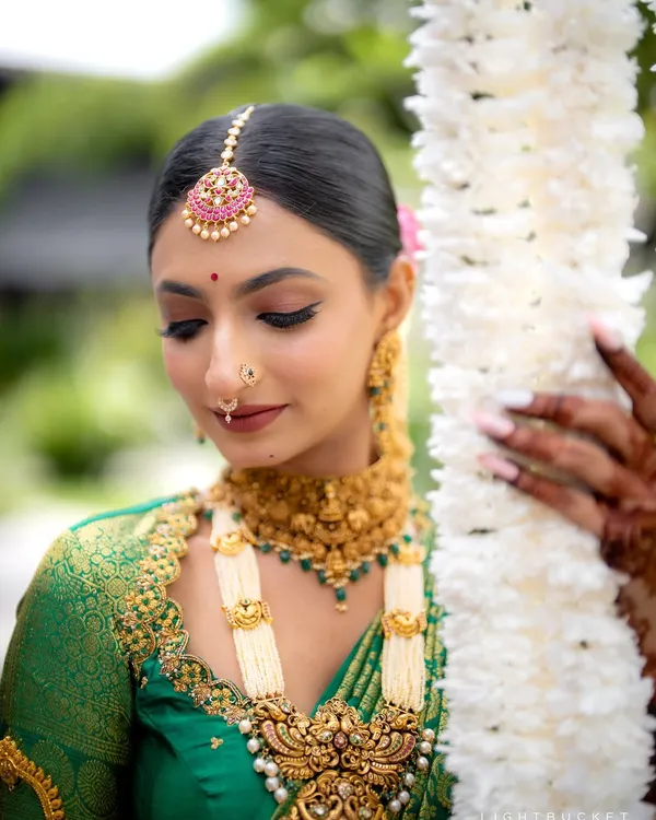 A close-up of the Muhurtham makeup, highlighting the defined eyes, perfectly blended skin, and traditional jewelry like the maang tikka and nose ring. This look is designed to be both elegant and long-lasting.
