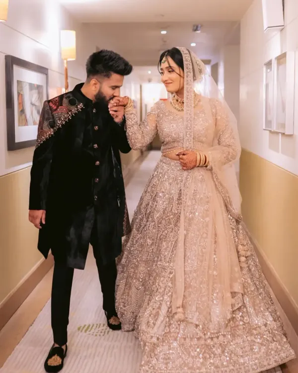 A moment of pure romance, captured forever. I designed this groom's attire to be a statement of modern royalty, featuring a custom black velvet sherwani with intricate, hand-embroidered shoulder details that complement the bride's ethereal lehenga.