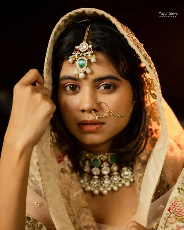 This is the kind of timeless bridal portrait I love creating. The focus is on the bride's expression, framed by the delicate details of her dupatta, with soft lighting that creates a classic, painterly feel. This is a moment of quiet confidence before the celebrations begin.