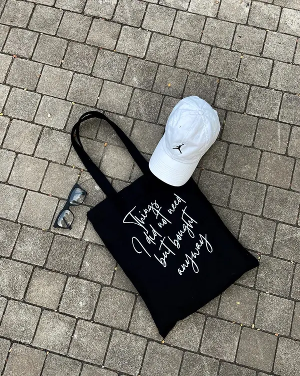 Our black tote with the "Things I did not need but bought anyway" script is a fan favorite. It's a fun, relatable accessory for any shopping trip, made from durable cotton that can handle all your finds.