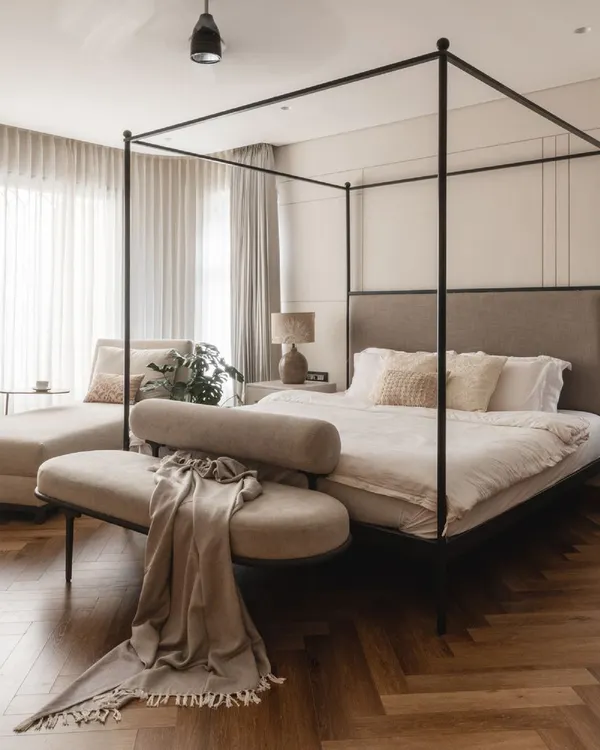 The focal point of this master bedroom is the stunning four-poster bed. The clean lines and dark frame create a modern canopy, while the soft, muted tones of the bedding and herringbone wood floor add warmth and gentle opulence.