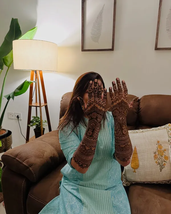A happy client playfully showing off her full-arm traditional mehndi. The joy and confidence that a beautiful design brings is what I aim for.