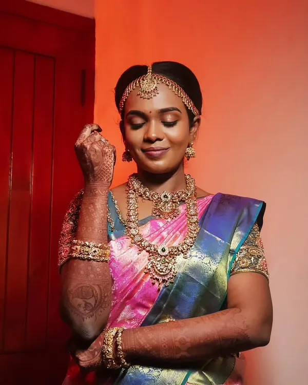 A classic muhurtham look for this beautiful bride. The makeup is kept traditional with defined eyes, a bold lip, and a flawless base that enhances her features and complements her stunning silk saree and gold jewelry.