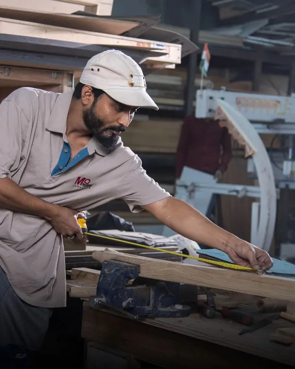 Behind every masterpiece are the hands of our skilled artisans. Here, one of our craftsmen meticulously measures and shapes a piece of wood, blending tradition with artistry. This dedication to handcrafted excellence is what breathes life into our luxury furniture.
