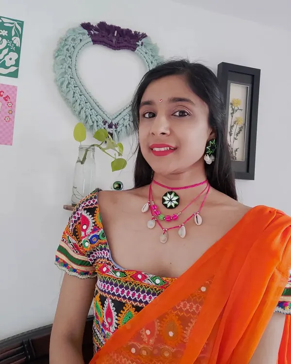 Here's how I styled this layered pink choker set for a Navratri look. It features a mirror work pendant, colorful beads, and cowrie shells, designed to complement a traditional embroidered blouse.
