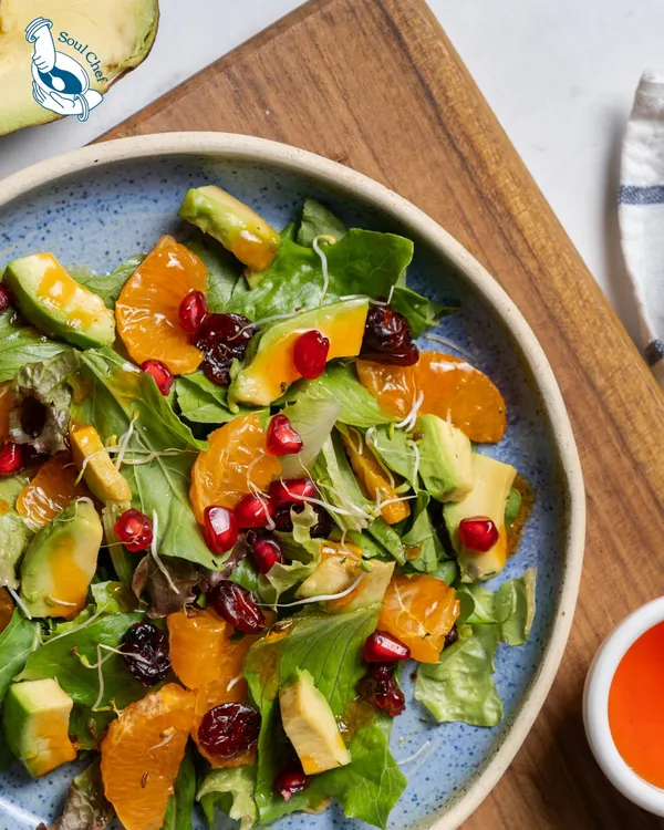 A feast for the eyes and the palate. This vibrant salad features mixed greens, creamy avocado, juicy mandarin oranges, tart cranberries, and a sprinkle of pomegranate seeds.