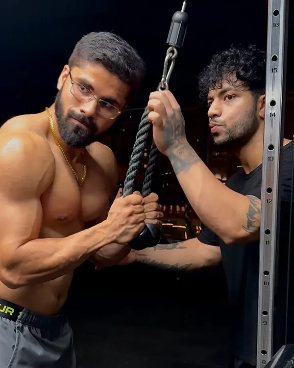In the gym, providing hands-on correction for a tricep pushdown. Proper form is non-negotiable for maximizing muscle growth and preventing injury.