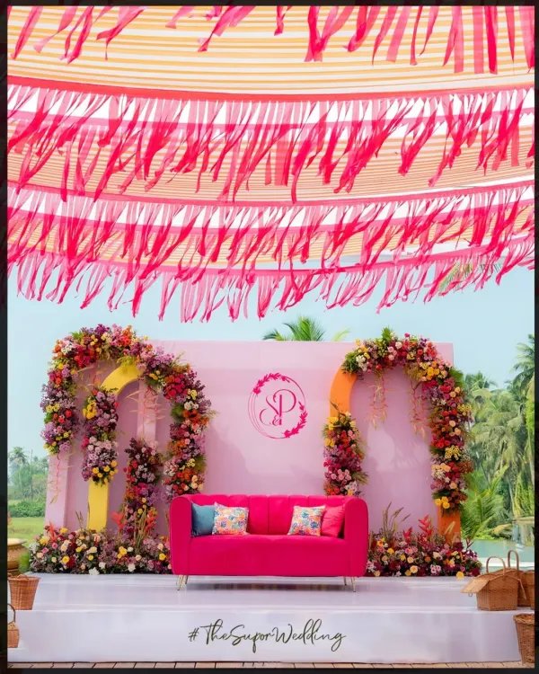 A perfect Haldi stage with a vibrant pink couch, colorful floral arches, and a fringed canopy. This setup at Alila Diwa Goa was all about creating a fun, quirky, and picture-perfect moment.