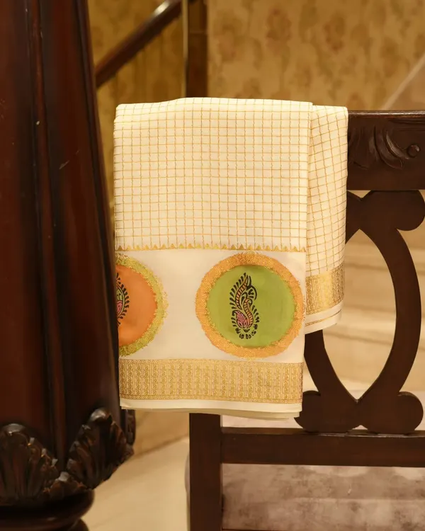 A royal cream and gold Mysore silk saree, distinguished by its shimmering gold zari checks and exquisite hand-block artistry. Mysore silk is celebrated for its softness and subtle sheen.