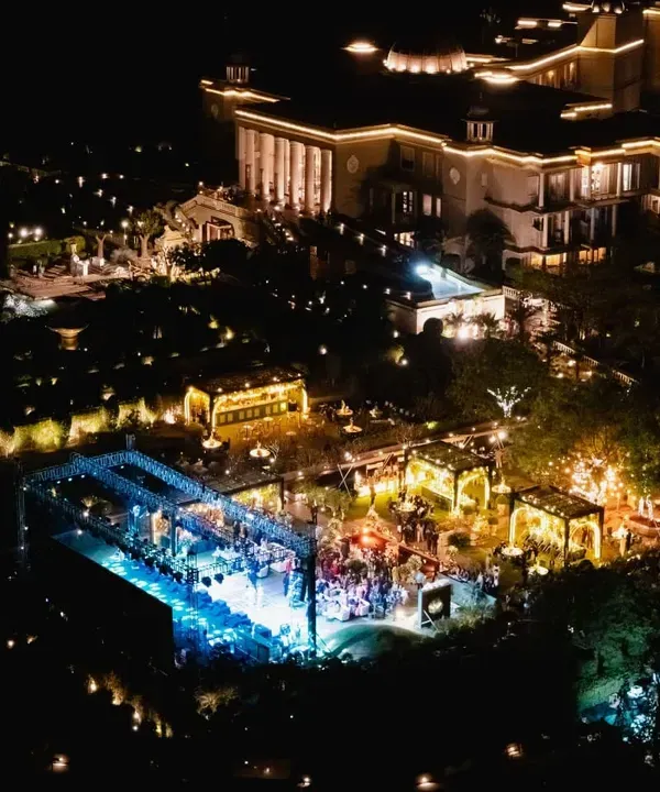 An aerial view of a welcome dinner at Raffles, Udaipur. The setup shows a dynamic layout with a grand stage for performers and elegant lounge areas, all illuminated to create a magical evening.