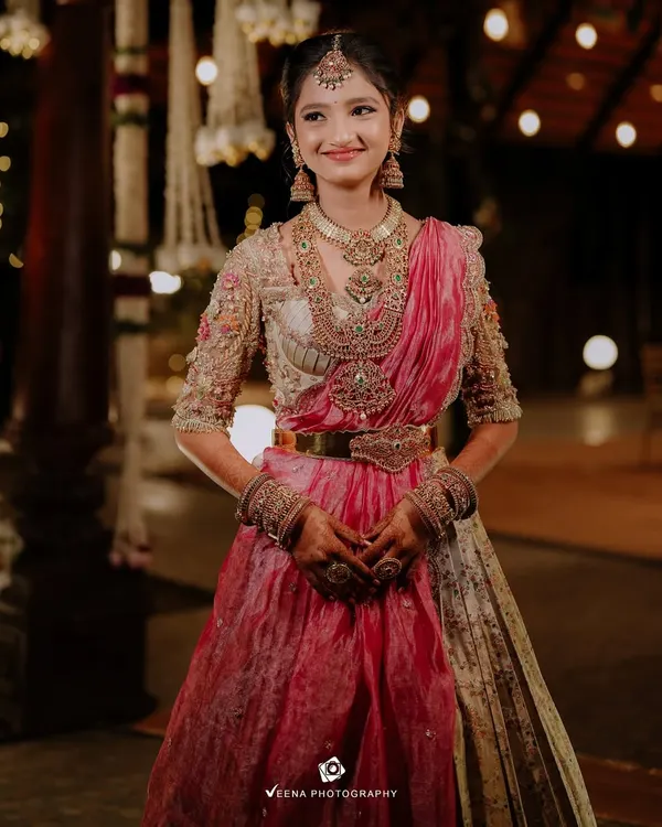 A Langa Voni is a beautiful choice for a half saree ceremony. This young client looks like a doll in her custom pink and gold outfit, featuring a hand-embroidered blouse and a traditional pattu skirt.