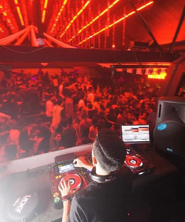 A view from my console overlooking a massive, packed dancefloor bathed in red light. This is the kind of full-house energy I consistently build and maintain throughout my sets.