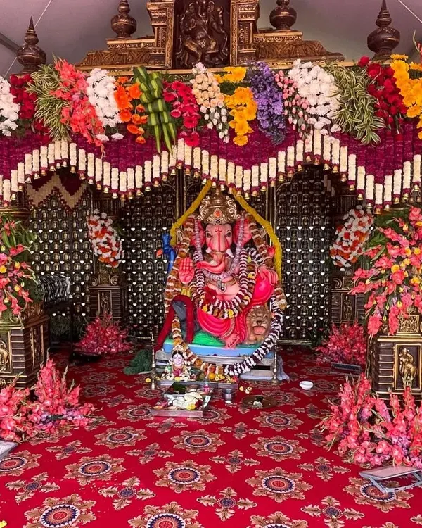For religious ceremonies like Ganesh Chaturthi or pre-wedding poojas, I create beautiful and respectful decorations. This setup features a grand floral pandal for the Ganesha idol, with vibrant flowers and a traditional red carpet.