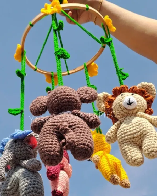 This jungle-themed baby cradle mobile features a whole crew of animal friends, including a lion, monkey, and elephant, hanging from a wooden hoop decorated with vines.