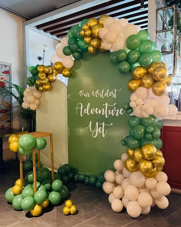 This "Our Wildest Adventure Yet" theme is perfect for adventurous parents-to-be. The setup includes a custom green backdrop and a balloon arch in shades of green, white, and gold, creating a stylish jungle vibe.