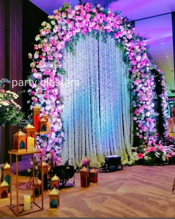 This grand floral arch serves as a stunning focal point. The mix of pink and white roses with a delicate jasmine curtain creates a luxurious and romantic atmosphere perfect for a reception entrance.