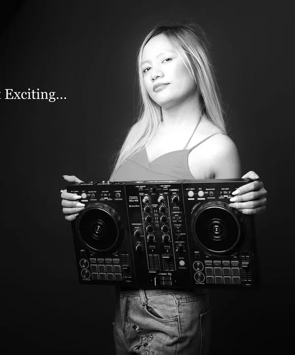 A moody black and white portrait of a DJ. The text overlay "Music makes it Exciting..." adds a graphic element, making this a cool, artistic shot for her profile.