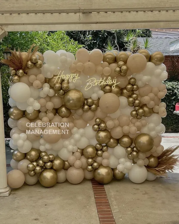 This full-wall balloon installation creates an incredible textured backdrop for photos. I used a mix of nude, white, and chrome gold balloons in various sizes and added a 'Happy Birthday' neon sign for a modern, chic look.