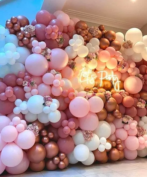 This vibrant "Let's Party" balloon wall is designed to make a statement. The mix of pink, rose gold, and white balloons with a central neon sign creates an energetic and fun photo backdrop.