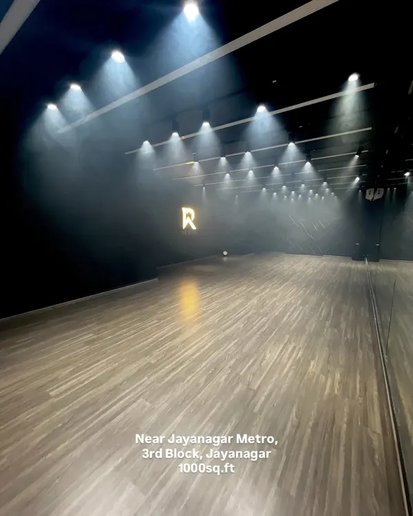Welcome to my Jayanagar studio. This is the moody, cinematic space you've been looking for, complete with professional track lighting, a smoke machine for atmosphere, and our signature 'R' logo wall. It's a 1000 sq.ft canvas ready for your next dance video, rehearsal, or photoshoot.