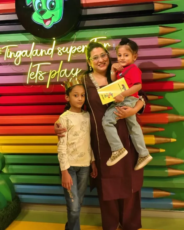 A mother and her two children pose happily, with the kids wearing fun paper crowns.