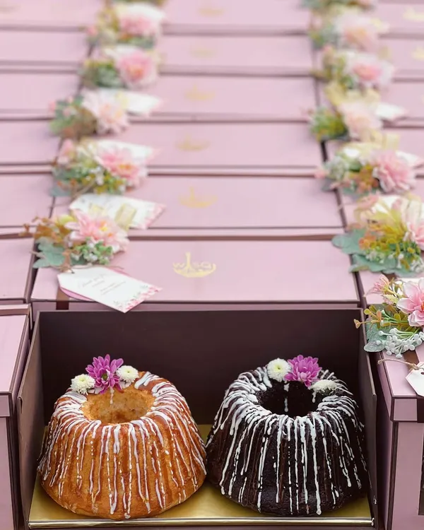 A close-up of our twin bundt cakes, a popular choice for return favours. This set includes one vanilla and one chocolate cake, both drizzled with icing and topped with delicate fresh flowers, ready to be gifted in our custom pink boxes.