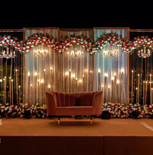 This is the kind of grand reception stage we love to create. The combination of warm lighting, cascading floral arrangements, and a dramatic backdrop makes for an unforgettable evening and stunning photographs. We can customize the scale and colors for your wedding reception.