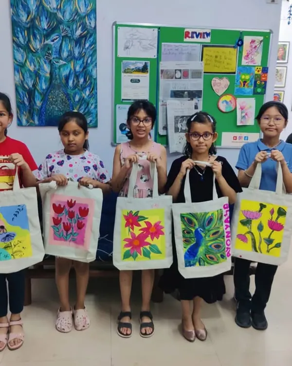 A group of proud young artists showing off their custom-painted tote bags. Our DIY workshops let kids create functional art they can use and be proud of.
