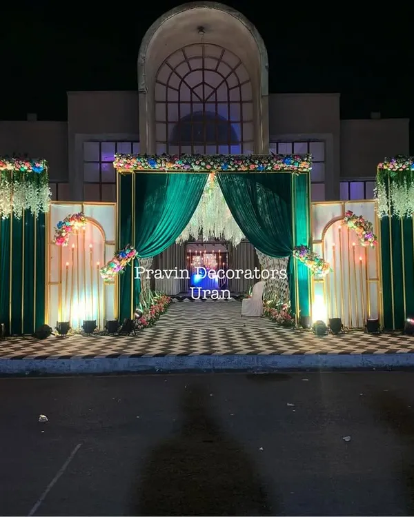 A truly grand entrance I created for an evening event. The structure features rich green velvet curtains, elegant white drapes, and floral arrangements, all beautifully lit against the night sky.
