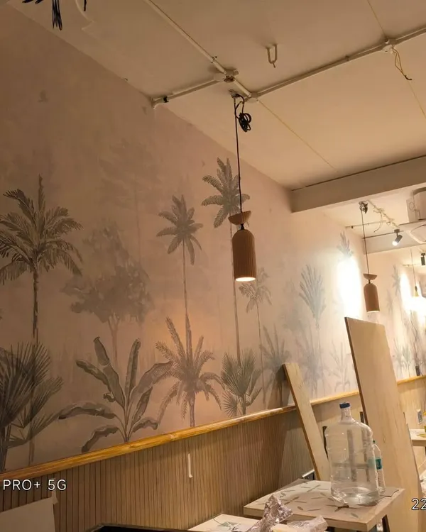 This is a cafe project in Bellandur where I installed a tropical-themed wallpaper above wooden wall paneling. This combination creates a stylish and inviting atmosphere for customers.