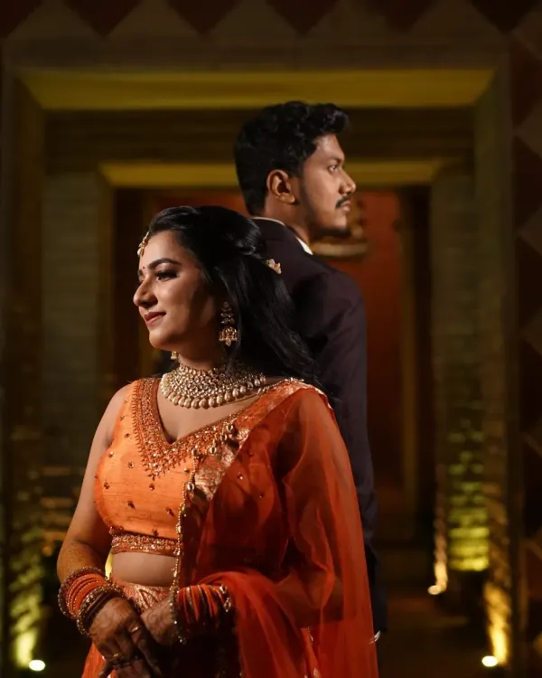 A romantic Sangeet look for the couple. The bride's orange lehenga is complemented by a soft, glowing makeup look.