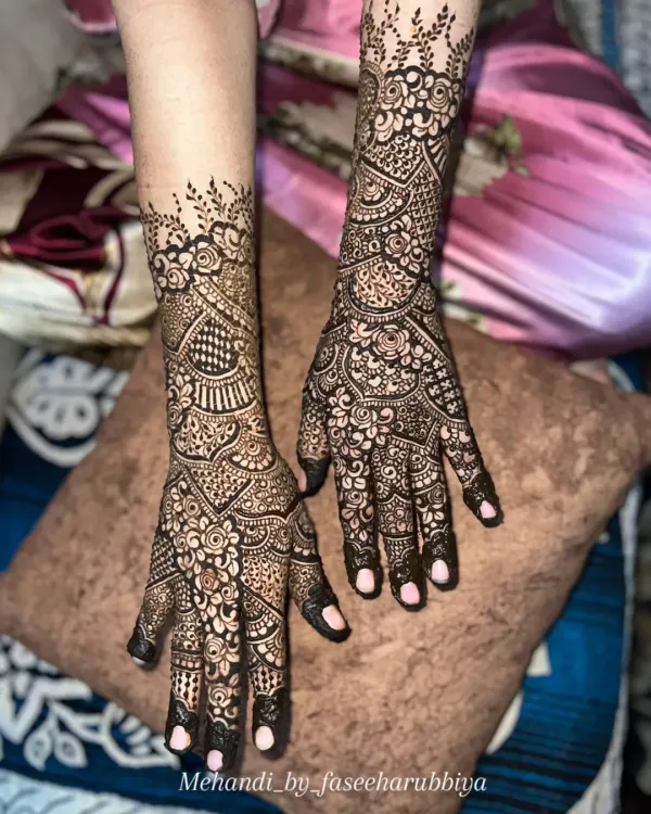 Intricate Indian henna extending to the mid-forearm. This design features a mix of paisleys, florals, and geometric fills.