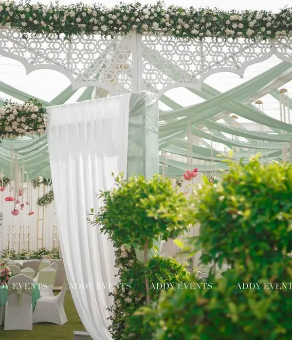 A grand and graceful entrance for a Nikah ceremony. This design for Khan Sir's wedding features a Mughal-inspired arch, pastel green drapes, and pristine white florals, creating a sophisticated and welcoming ambiance.