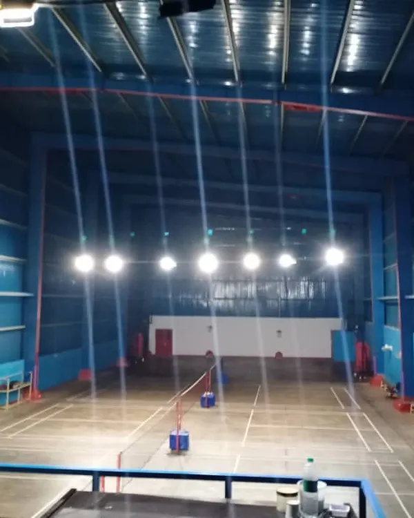 A clear view of our well-maintained, empty badminton courts. This image showcases the professional line markings, high ceilings, and powerful overhead lighting system that ensure optimal playing conditions at any time of day.