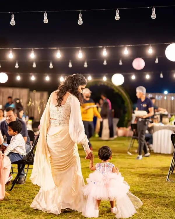 A mother and daughter walking hand-in-hand under a canopy of lights. We design our events to create beautiful, memorable moments like this.