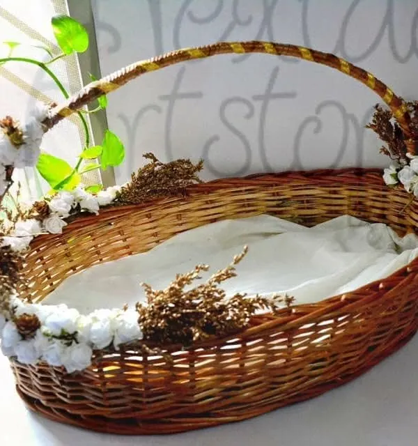 This is an example of a custom-decorated hamper basket, perfect for weddings or special events. The sturdy oval cane basket is adorned with flowers and lined with fabric, ready for gifting.