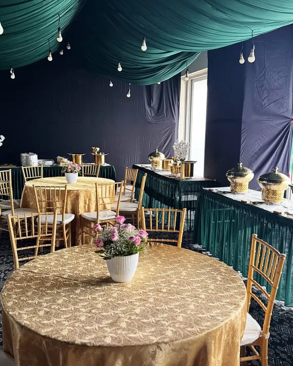 A complete view of our event styling. We coordinated the gold brocade tablecloths and chiavari chairs with the emerald green ceiling drapes and buffet skirting to create a rich, celebratory atmosphere.