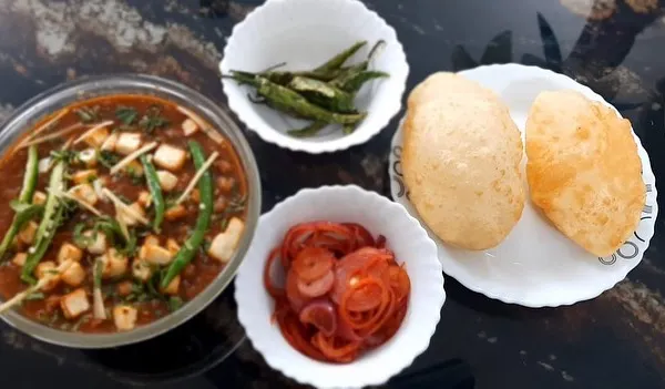 Our weekend special: home-cooked Chole Bhature. The spicy chole masala is served with fluffy bhature, pickled onions, and fried green chillies.